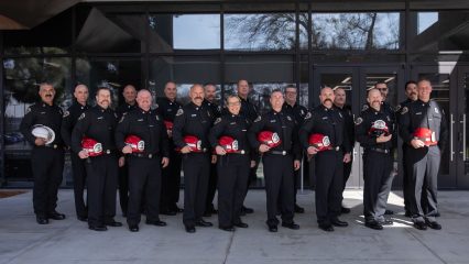 A group of newly promoted County Fire battalion chiefs and captains pose for a photo in front of a building.