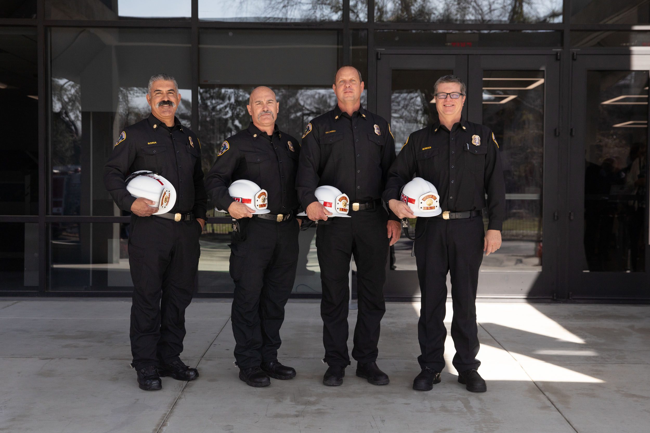 A group of newly promoted County Fire battalion chiefs pose for a photo in front of a building.