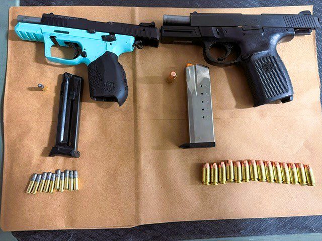 Two disassembled guns with bullets laid out on a brown background.